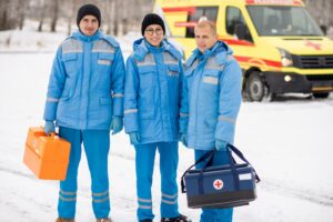 Brigade of young paramedics in blue workwear and gloves holding first aid kits