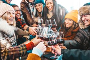 Happy multiracial friends toasting red wine at restaurant terrace