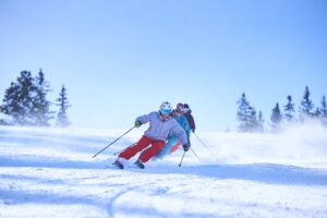 Row of male and female skiers skiing down snow covered ski slope, Aspen, Colorado, USA